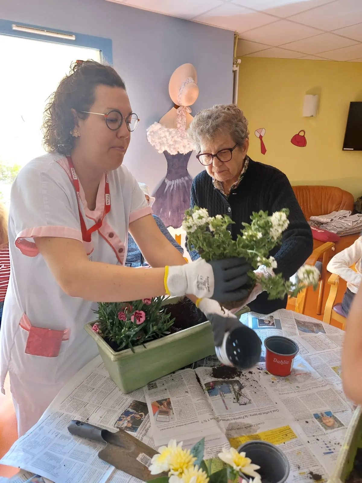 Résidente composant une jardinière fleurie avec une soignante