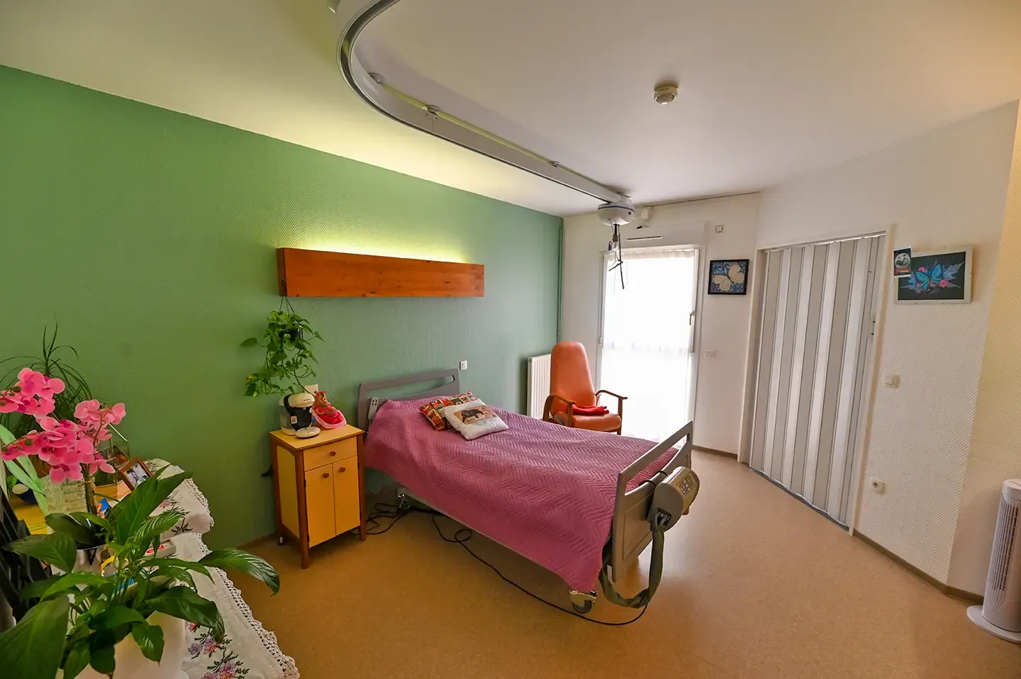 Chambre lumineuse aux murs verts avec lit médicalisé