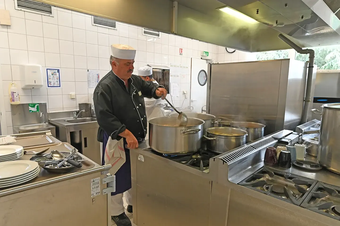 Le chef cuisinier aux fourneaux dans la cuisine de l'établissement